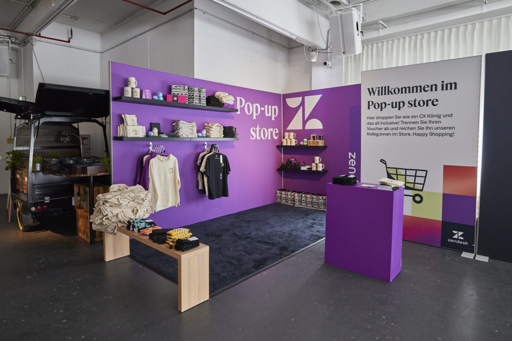 Zendesk Pop-up Store mit Merchandise-Produkten vor lila Wand